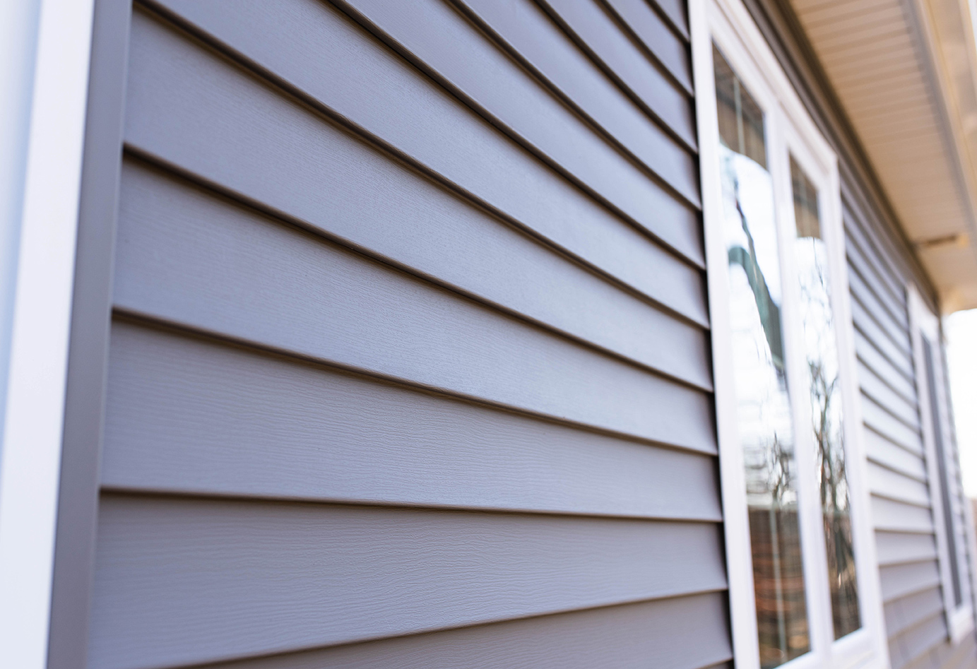 Gray horizontal siding on a house exterior. White window frame.