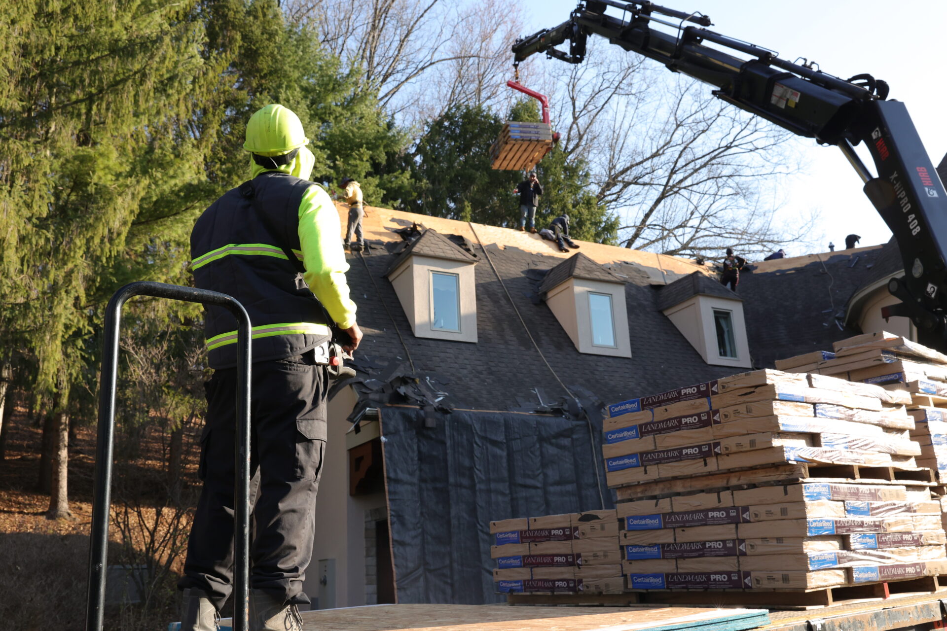 A roofer in safety gear unloading shingles