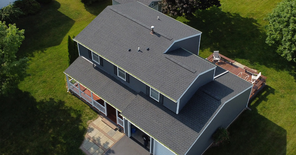 Gray house with a deck and green lawn. Aerial view of a residential property.