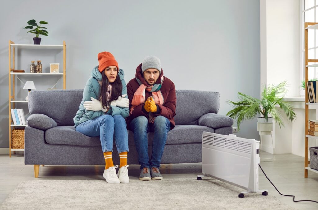 two people sitting on a couch bundled up in winder gear