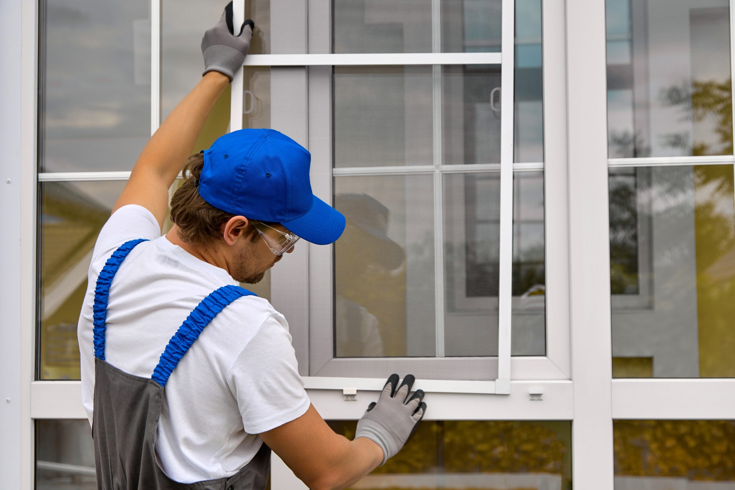 Worker in blue cap installing window. Window installation process.