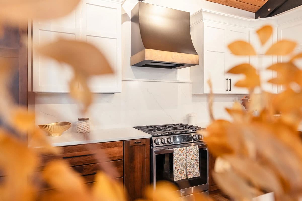A modern kitchen with white cabinets, stainless steel appliances, and a range hood. The kitchen is well lit and clean.