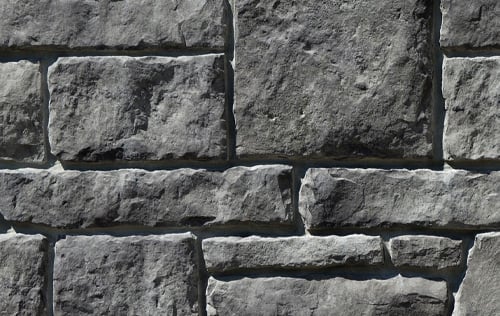 Grey stone brick wall. A close-up of a grey stone brick wall with a rough texture.