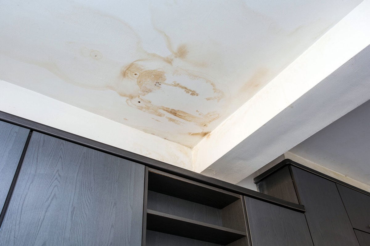 Water Stain on Ceiling Above Dark Cabinets Brown water stain on white ceiling. Stain above kitchen cabinets.