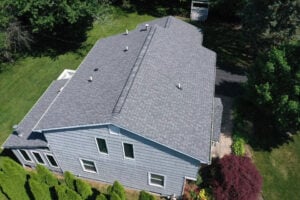 A house with a gray roof and blue siding. The house has several windows.