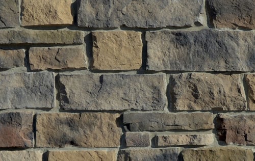 Brown stone brick wall. Gray mortar between bricks.