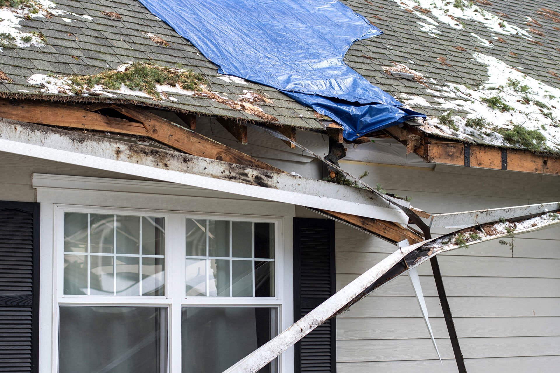 Damaged roof with tarp covering. Roofing issues.