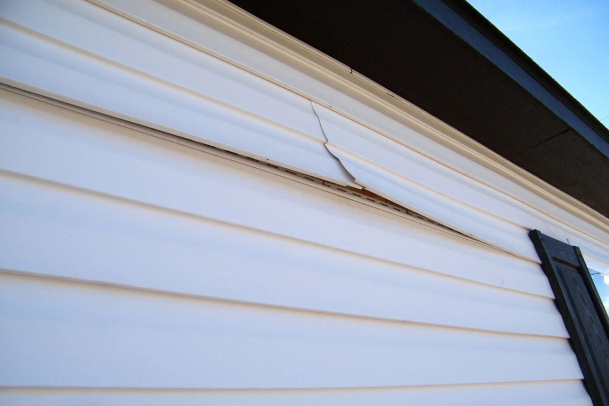 Cracked siding on a house. Damaged exterior wall.