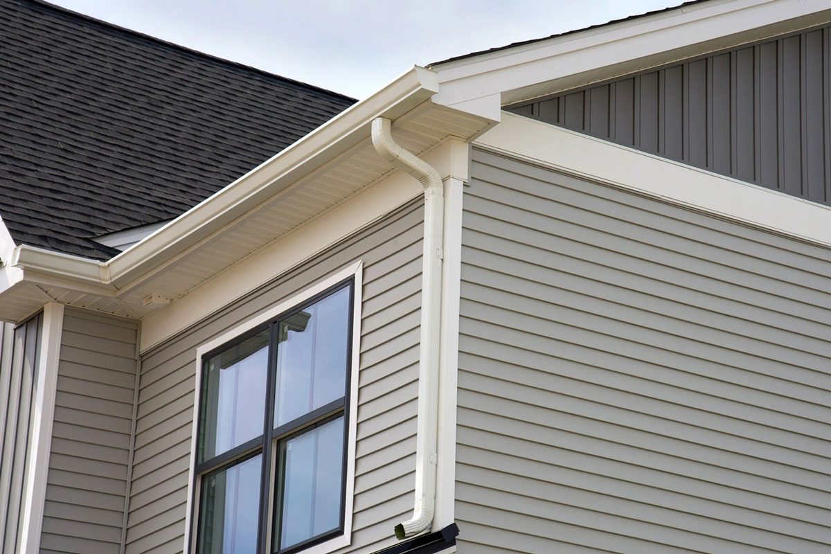 A house with gray siding and white gutters. The house has a large window.