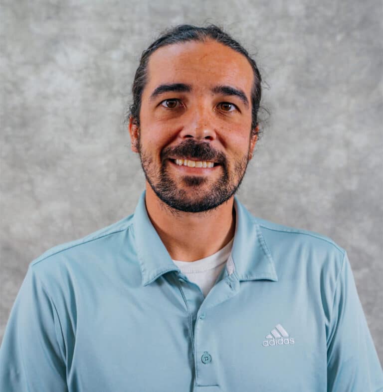 Smiling Man in Light Blue Adidas Polo Shirt A man with a beard and mustache wearing a light blue Adidas polo shirt. He is smiling at the camera.