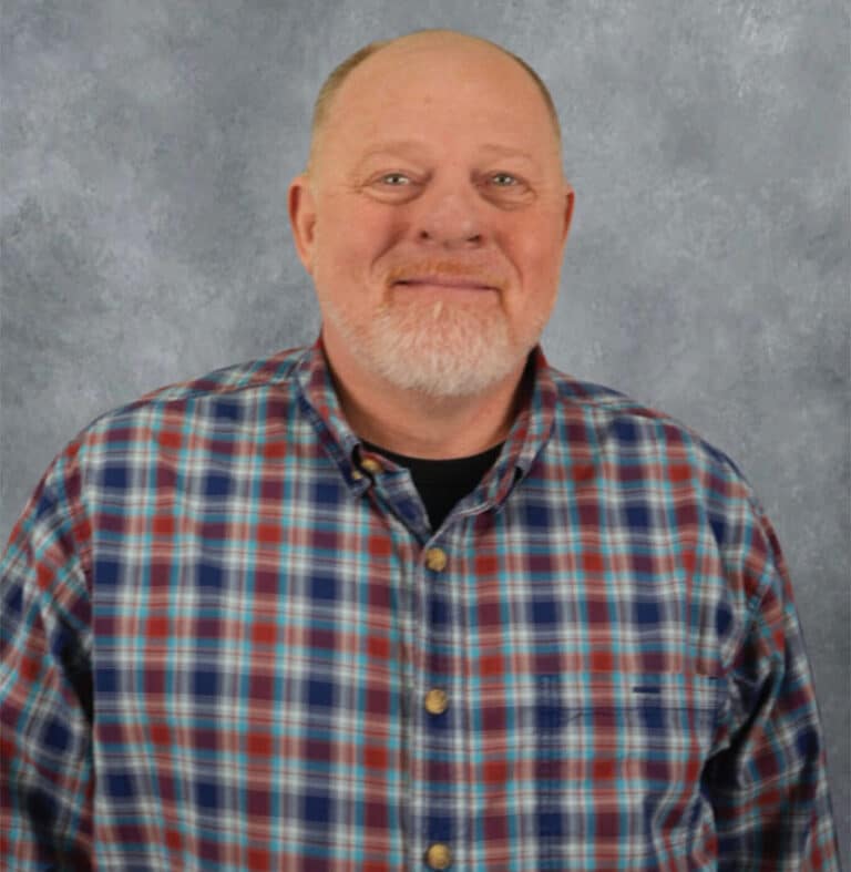 Smiling middle-aged man in plaid shirt A man with a white goatee smiles