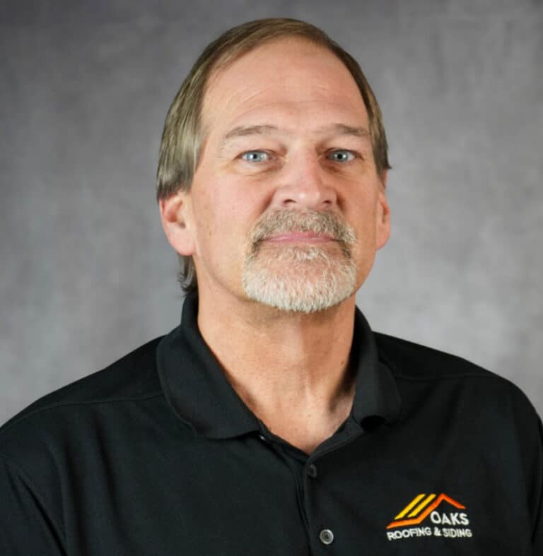 Portrait of a man with a goatee and company logo Man with a goatee wearing a black polo shirt with a logo.