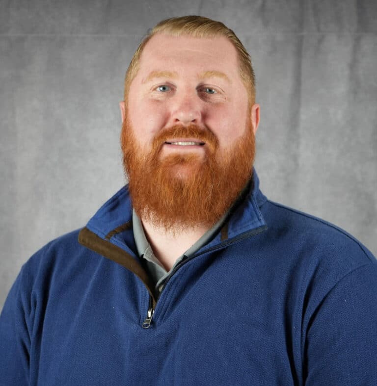 Portrait of a smiling man with red hair and beard A man with red hair and a beard smiles at the camera. He is wearing a blue sweater.