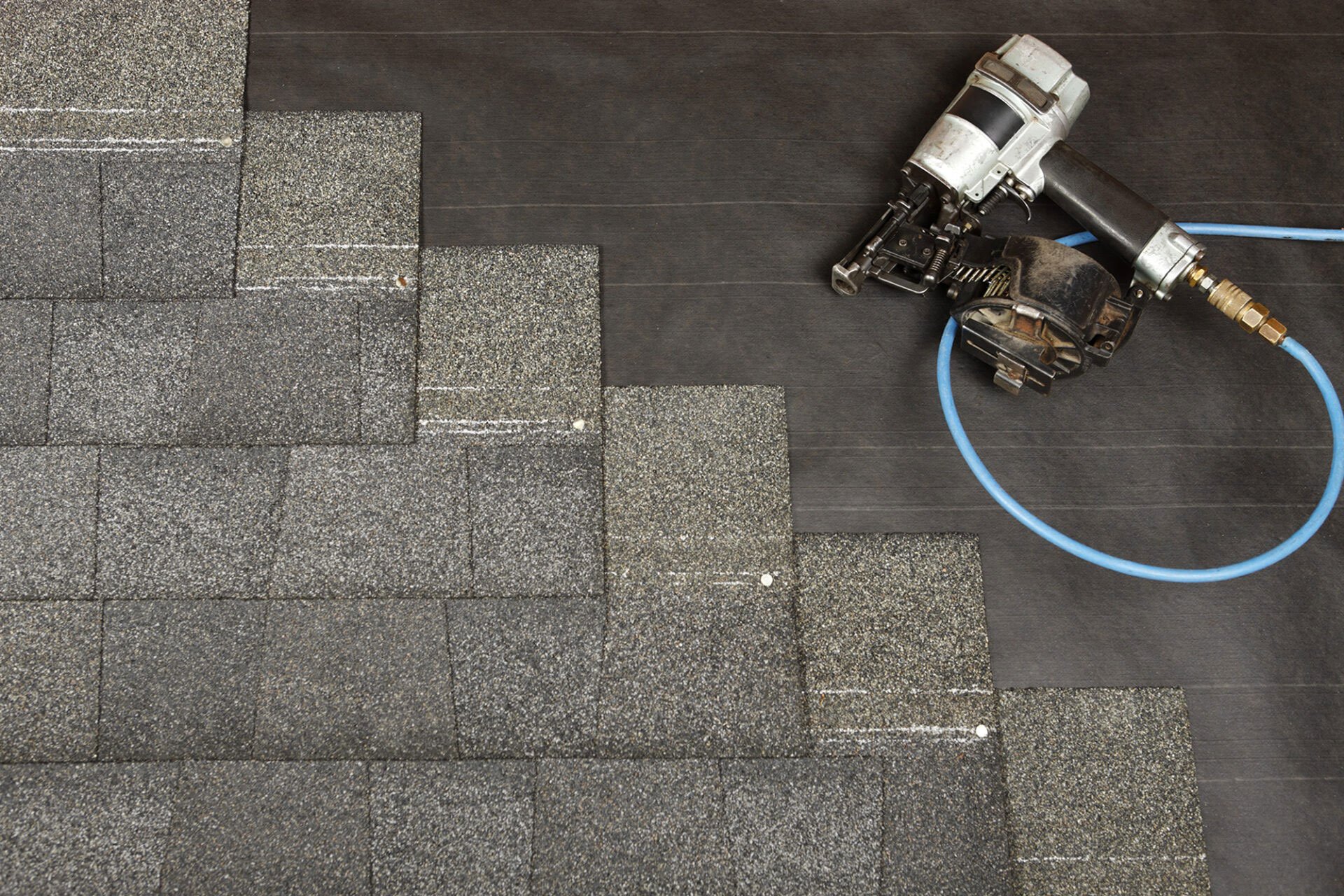 Roofing shingles and a roofing nailer. Roofing tools on a roof.