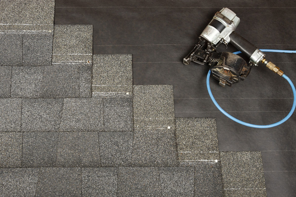 Roofing shingles with roofing equipment and hose Roofing shingles with equipment. A roofing tool with a blue hose.