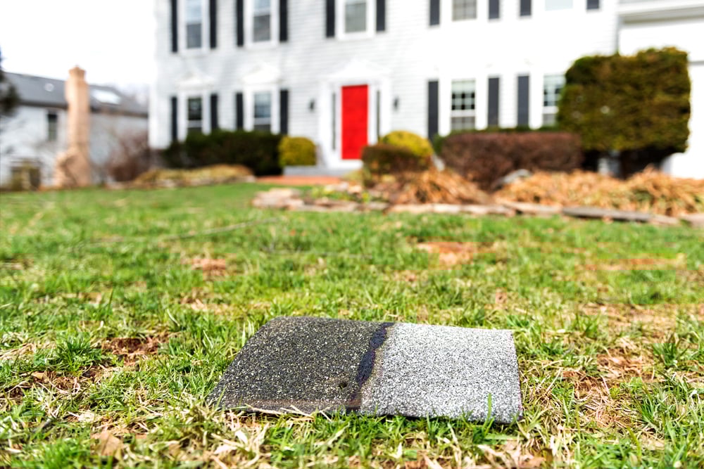 Two stones on grassy lawn in front of house Two grey stones on a grassy lawn. A house with a red door in the background.