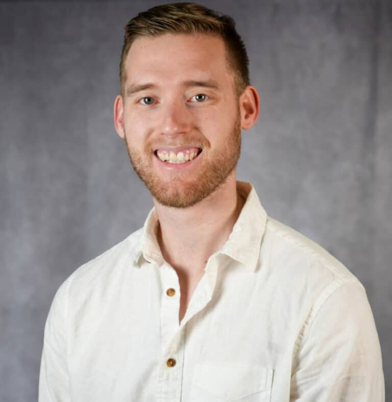 young man with short brown hair and white shirt A smiling young man with short brown hair and a white button down shirt.
