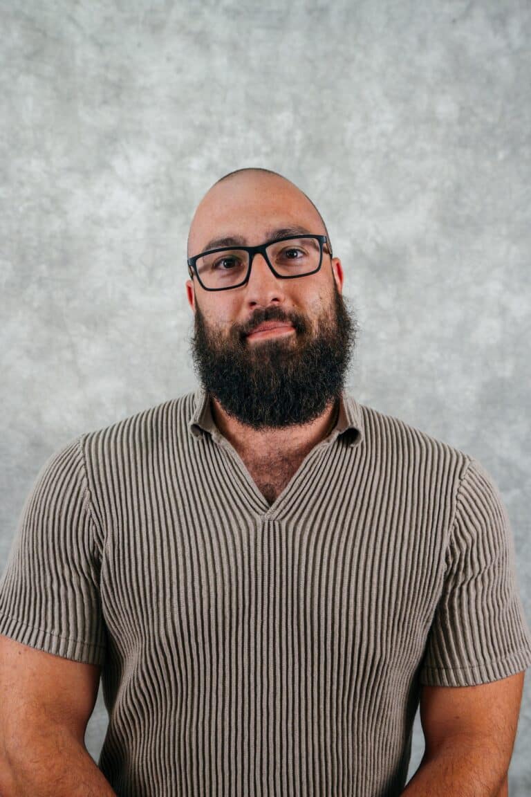 Portrait of a man with a beard and glasses Man with beard and glasses looking forward. He is wearing a striped shirt.