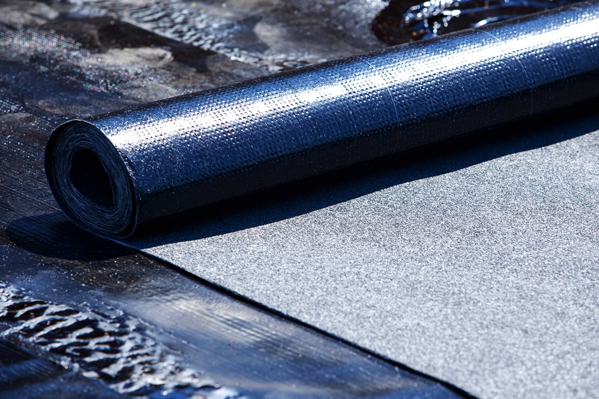 A roll of black foam insulation material. Unrolled insulation board.