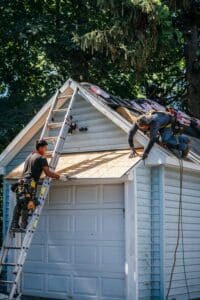 Two roofers working on a garage roof.