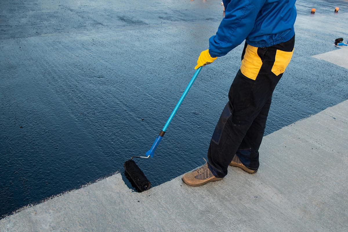 A worker in protective gear applying a sealant.
