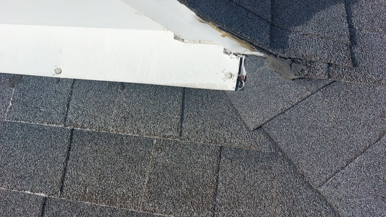 A closeup of roof shingles and damaged soffit. Roofing repair and replacement.