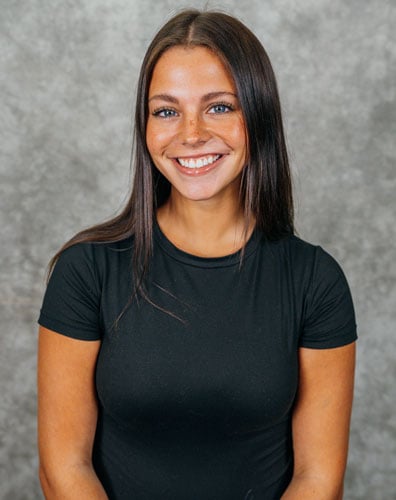 A young woman with long dark hair and a black t-shirt smiling at the camera.