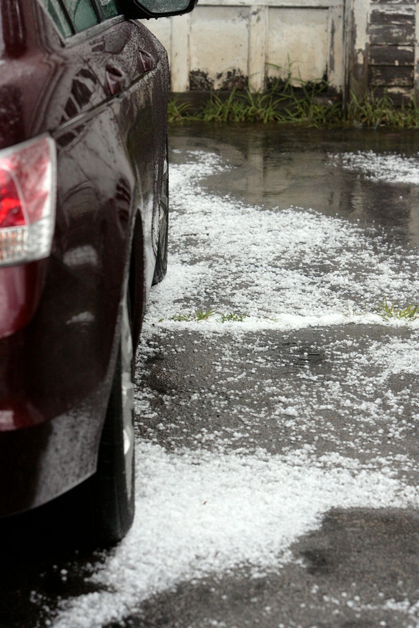 Hail on the ground beside a car.