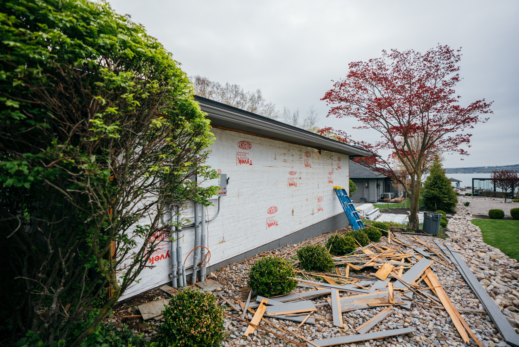 A house with exposed insulation and debris on the ground.