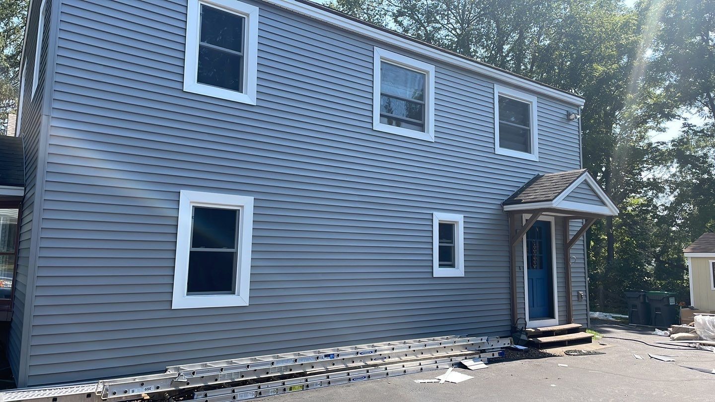 A two-story gray house with white trim around windows and a blue front door.
