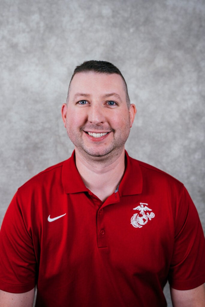 A man wearing a red polo shirt with a white Nike swoosh and Washington State University logo smiles at the camera.