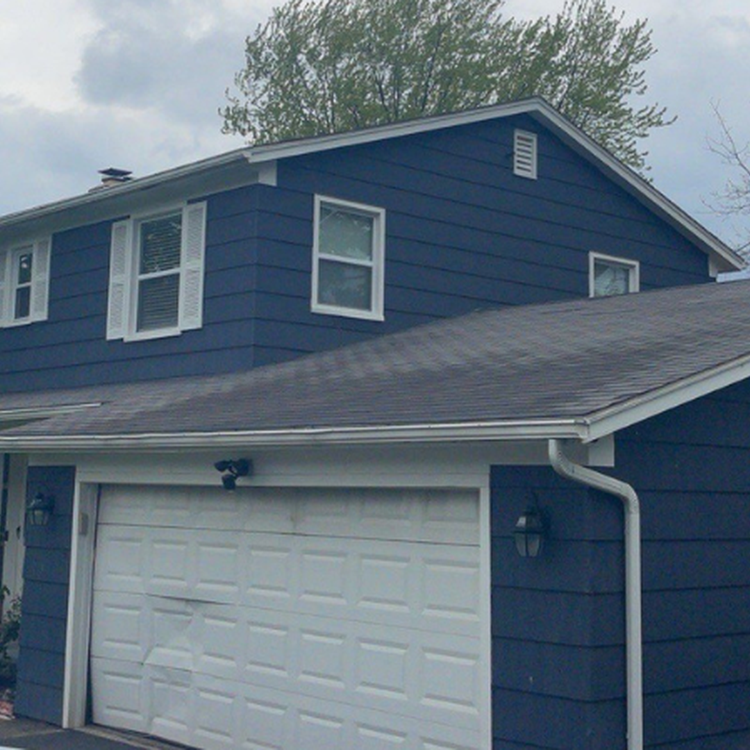 Front view of a contemporary house featuring navy siding and a white garage.