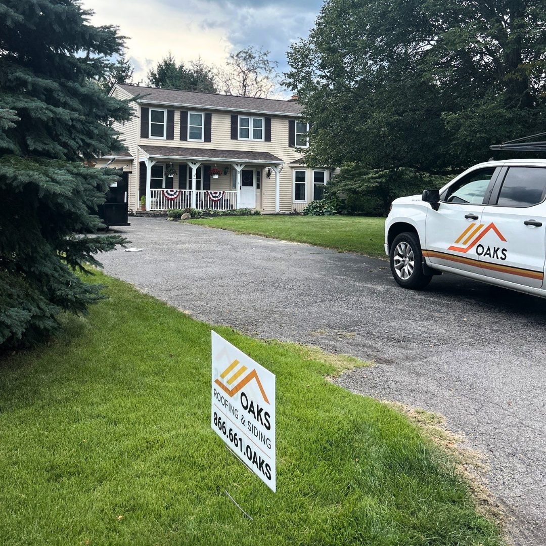 A white Oaks Roofs and Siding service truck parked on a driveway.