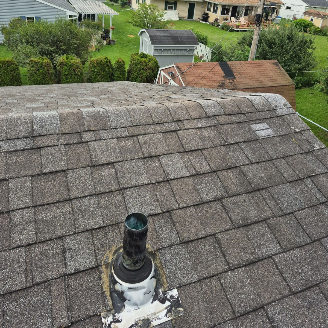 High angle shot of a grey asphalt shingle roof with copper plumbing vent.