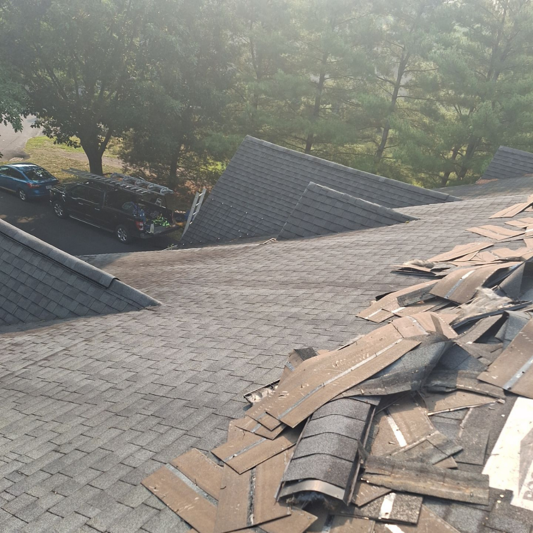 A residential roof in the process of shingle replacement showing old shingles being removed and new ones being installed.