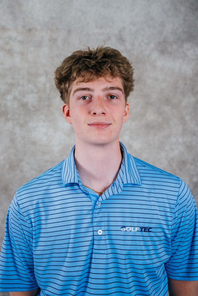 Portrait of a teenage boy with curly brown hair wearing a blue striped polo shirt.