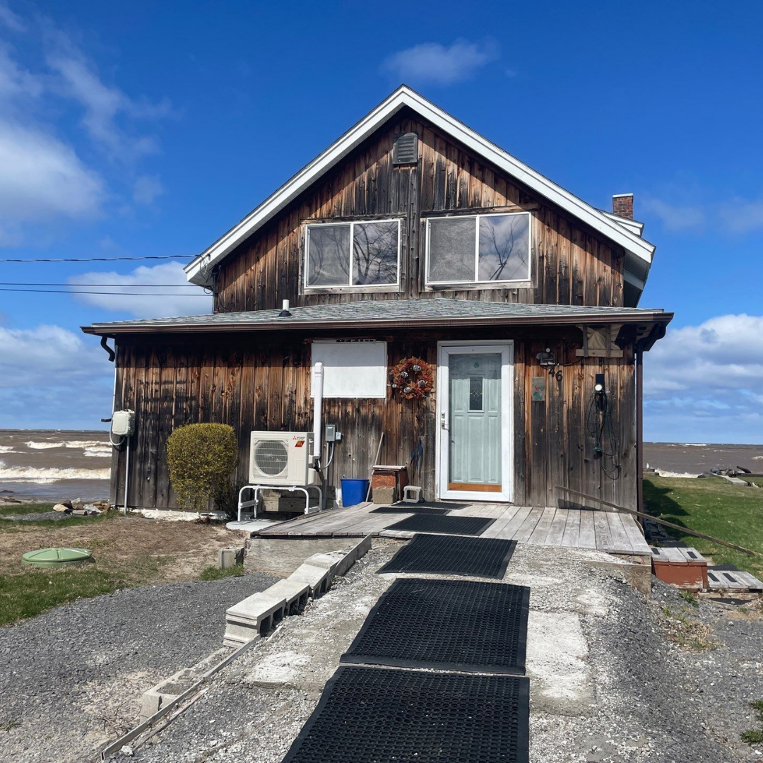 Wooden cabin with light blue door and black walkway under clear blue sky