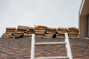 Stacks of shingles on a roof during replacement with a ladder.