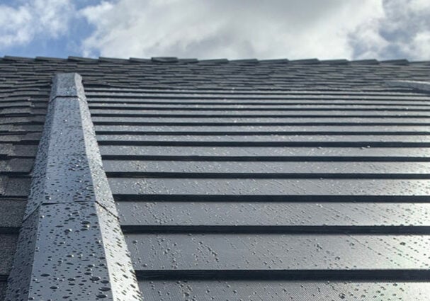 Roof with grey shingles on cloudy day Grey roof shingles on a cloudy day. Water droplets on the shingles.