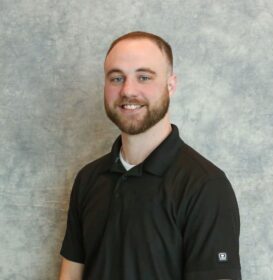A man with a beard and short hair wearing a black polo shirt