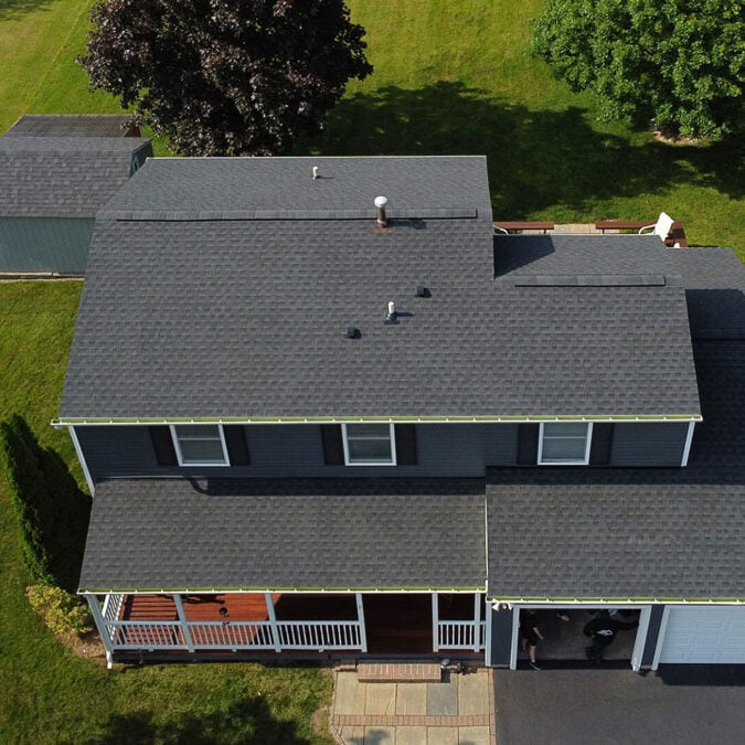Aerial View of Two Story House with Gray Roof Overhead view of a two-story house with a gray roof and green lawn. The house features a covered porch and garage.