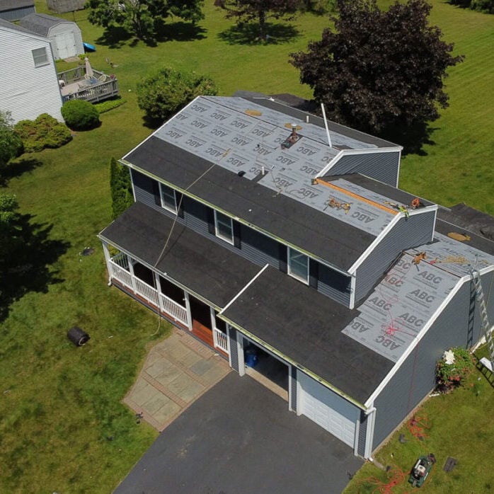 A house with a partially removed roof. Workers are on the property.