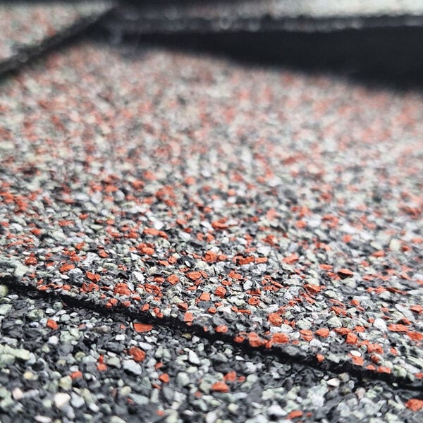 Asphalt Shingles Roofing Close-up Close-up view of asphalt shingles with orange, gray and black colors. Roofing material with textured surface.