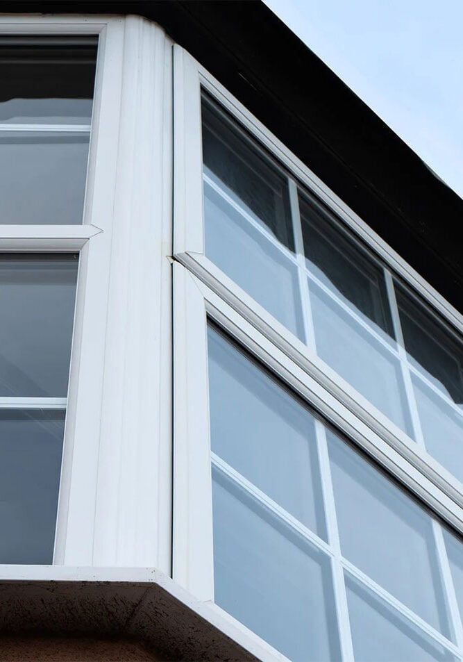 White Bay Window on Brick Building Exterior A white bay window on a brick building. The window has multiple panes.