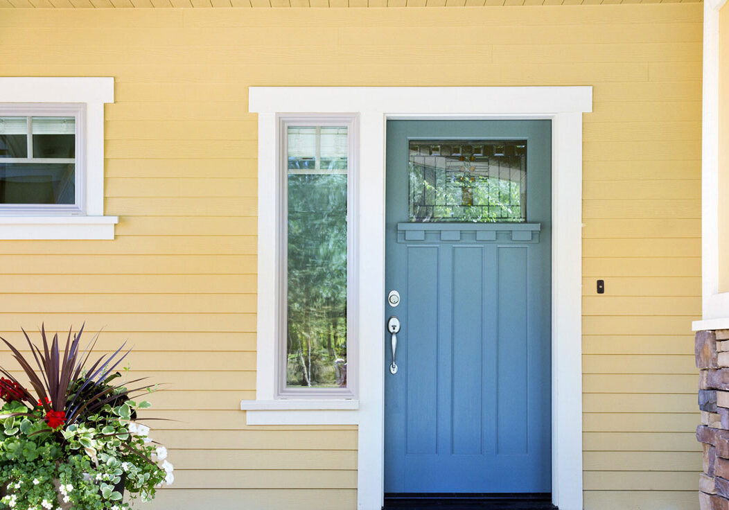 Blue front door with white trim on yellow house Blue front door with white trim on yellow house. A window beside the door.