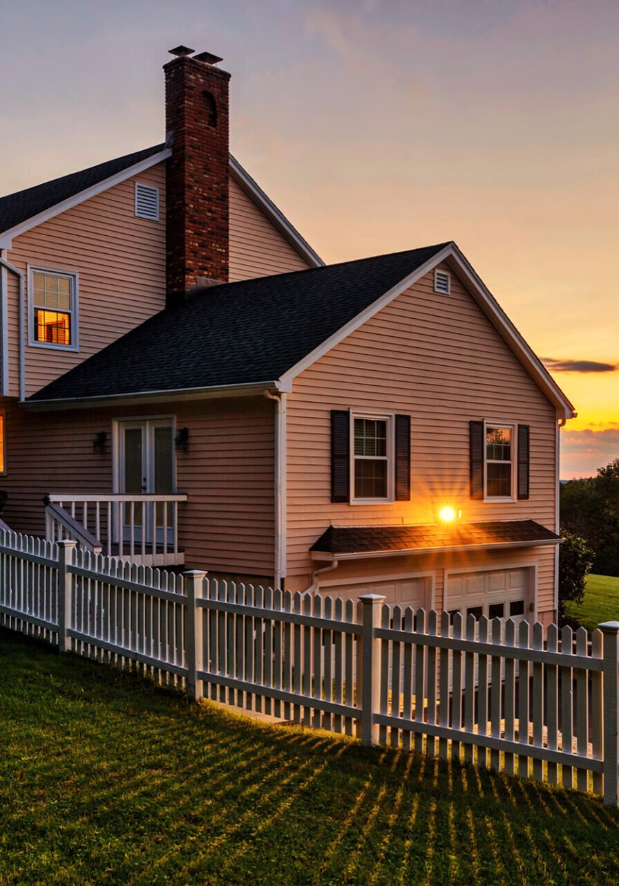 Cozy house with white picket fence at sunset Beautiful house with a white picket fence. Peaceful suburban home.