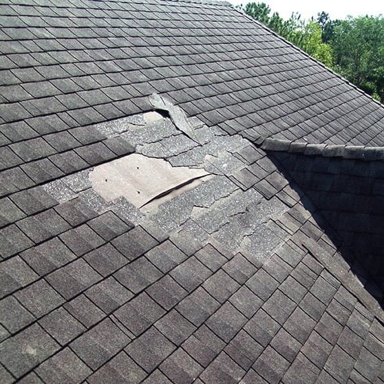 Damaged Roof Shingles with Missing Pieces Damaged roof shingles. A close-up view of a roof with missing shingle pieces.