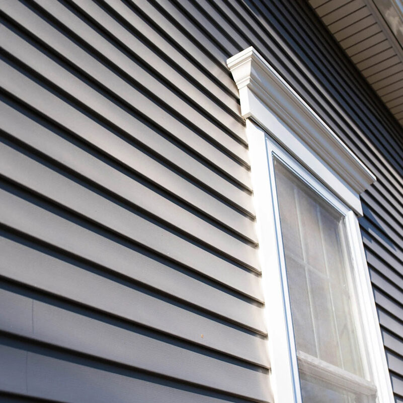 Dark gray house siding with white window trim Gray house exterior with white window frame. Horizontal siding.