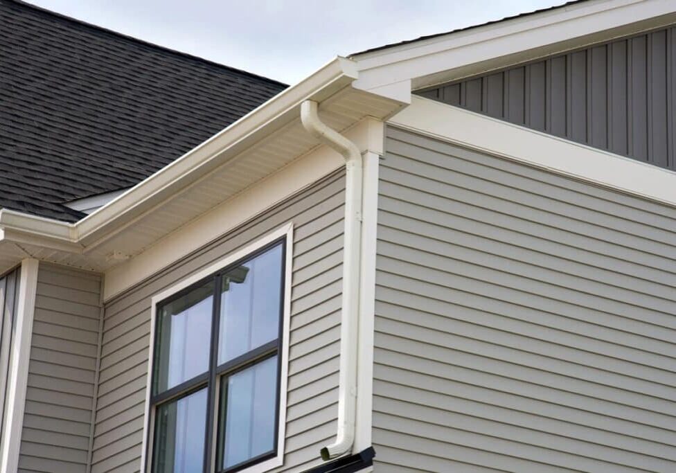 A house with gray siding and white gutters. The house has a large window.