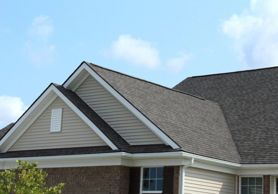 Roof of a house with gray shingles and white trim A house with a gray roof and white trim around windows.